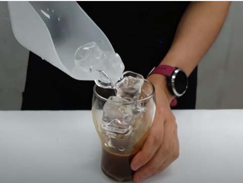 adding some ice cubes into the cup