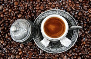 Turkish Coffee cup having coffee in it and coffee beans are spread around the cup